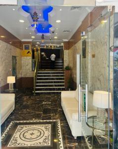 Safari Hotel Apartments في عجمان: لوبى به أريكة ودرج مع ضوء أزرق