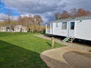 a small white trailer sitting in a yard at HARRIES LODGE QUAY WEST milkwood way in New Quay