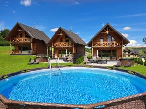 a house with a swimming pool in front of a house at Sołtysie Chaty - Domek z prywatną balią in Łapsze Niżne