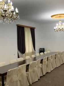 una sala de conferencias con sillas blancas y una lámpara de araña en Hotel Villa DavidL, en Sagarejo