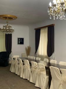 Habitación con mesa con sillas blancas y lámpara de araña. en Hotel Villa DavidL, en Sagarejo