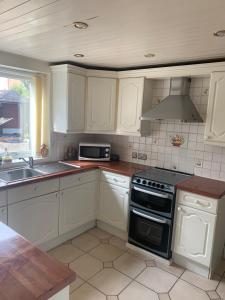 uma cozinha com armários brancos e um forno com placa de fogão em Comfort Home em Wigan