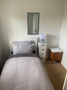 a bedroom with a bed with a mirror and a nightstand at Comfort Home in Wigan