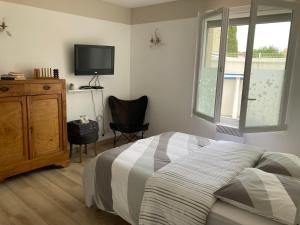 a bedroom with a bed and a tv and a chair at Chez Val et Phil in La Voulte-sur-Rhône
