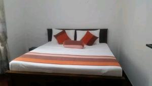 a bed with orange and orange pillows in a room at The European Gate - Anuradhapura in Anuradhapura