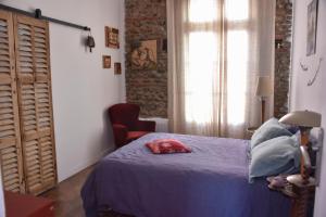 um quarto com uma cama, uma cadeira e uma janela em La Maison d'Elysa em Perpignan