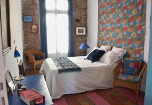 um quarto com uma cama grande e uma cadeira em La Maison d'Elysa em Perpignan
