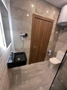 a bathroom with a toilet and a wooden door at La Bella Guesthouse in St. Julianʼs