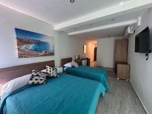 a hotel room with two beds and a television at La Bella Guesthouse in St. Julianʼs