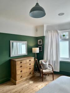 a bedroom with a dresser and a mirror and a chair at Palm - Bournemouth in Bournemouth