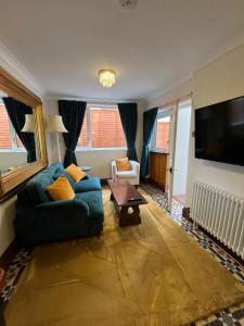 ein Wohnzimmer mit einem blauen Sofa und einem TV in der Unterkunft Captain's Nook, Luxurious Victorian Apartment with Four Poster Bed and Private Parking only 8 minutes walk to the Historic Harbour in Brixham