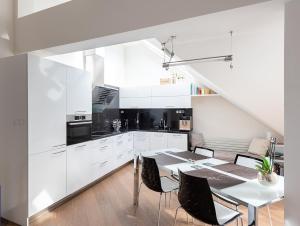 een keuken met witte kasten en een tafel met stoelen bij Luxusní apartmán s výhledem in Praag