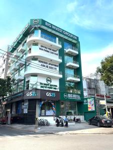 un grand bâtiment vert et blanc avec des motos garées devant dans l'établissement BIG Hotel Sài Gòn, à Hô-Chi-Minh-Ville