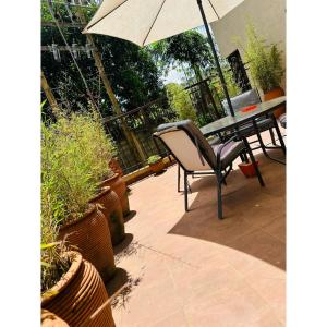 a patio with a table with an umbrella and potted plants at Westpoint suites in Nairobi