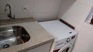 una pequeña cocina con fregadero y lavadora en Edifício Dalpiaz, en Balneário Camboriú