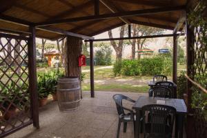 a patio with tables and chairs and a tree at Area Sosta La Pampa in Marina di Grosseto