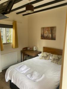 a bedroom with a bed with white sheets and a desk at The Wheatsheaf in Bramley
