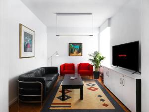 Hestia Anemone - Spacious Apartment in Kolonaki في أثينا: غرفة معيشة مع أريكة جلدية سوداء وكراسي حمراء