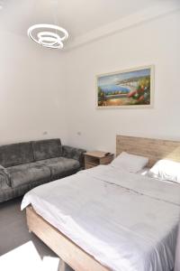 1 dormitorio con cama blanca y sofá en Hotel Termal, en Peshkopi