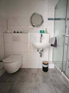 a bathroom with a sink and a toilet and a mirror at MiNe Hotel in Weilerswist +27 photos