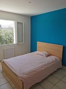 a bedroom with a large bed with a blue wall at Villa 7/8p Pierrevert in Pierrevert