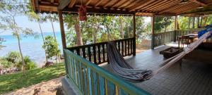 a hammock on the porch of a house overlooking the ocean at Alam Kita in Karimunjawa