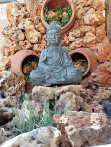 uma estátua de um Buda sentado em frente a uma parede de pedra em Chania Hostel Youth em Chania Town