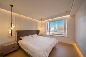 上海Moli B&B - Bund River View Near Yu Garden subway 3bedrooms 2bathrooms 1bathtube with elevator apart ment的卧室里有一张白色的大床，床边有一扇窗户