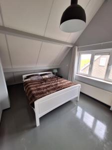um quarto com uma cama num quarto com uma janela em Vrijstaande vakantie woning em Wolphaartsdijk