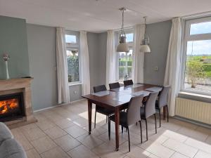 uma sala de jantar com uma mesa e cadeiras e uma lareira em Vrijstaande vakantie woning em Wolphaartsdijk