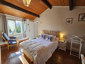 a bedroom with a bed and a chair and a window at Gîte des Gravets in Sigalens