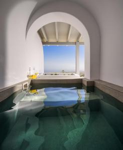 a bathroom with a pool of water and a bath tub at Lotus Suites in Fira
