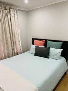 una camera da letto con un letto bianco con cuscini colorati di Kya Sand Guesthouse a Johannesburg