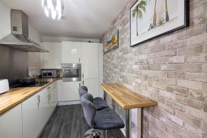 una cocina con armarios blancos y una pared de ladrillo en Paradise Lodge Chill Condo, en Mánchester