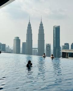 un grupo de personas nadando en una piscina infinita con vistas al perfil urbano en EATON RESIDENCE KLCc, en Kuala Lumpur