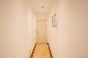 a hallway with a white wall and a white door at Duomo Boutique Hotel in Chioggia