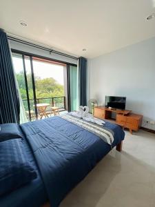 1 dormitorio con cama azul y ventana grande en Triple O Phala Beach en Ban Phala