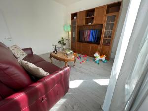 “Al 57”…. a quiet corner in Ferrara في فيرّارا: غرفة معيشة مع أريكة حمراء وطاولة