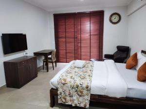 a bedroom with a bed and a desk and a television at Aloha Apartments by blissful Ganges in Rishīkesh