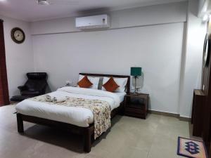 a bedroom with a bed and a chair at Aloha Apartments by blissful Ganges in Rishīkesh