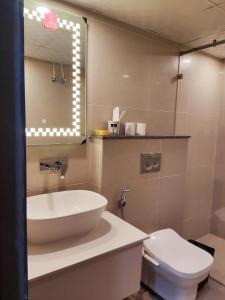 a bathroom with a sink and a toilet and a mirror at Aloha Apartments by blissful Ganges in Rishīkesh