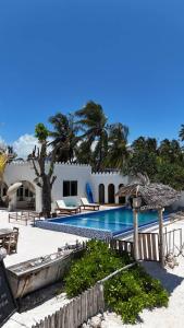 un complejo con piscina y palmeras en Coco Beach Hotel, en Jambiani