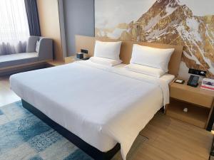 uma grande cama branca num quarto de hotel em Tuke China Hotel Shanghai Hongqiao Airport em Xangai