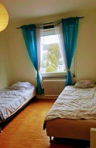 a bedroom with two beds and a window with blue curtains at Bravo in Malmö