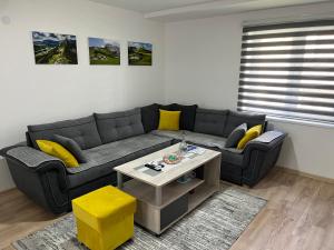 a living room with a black couch and yellow pillows at Apartman 4M in Foča