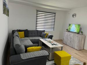 a living room with a gray couch and yellow pillows at Apartman 4M in Foča