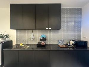 a kitchen with black cabinets and a black counter top at The Rooftop Townhouse in Center of Pattani in Kampong Rusamileh