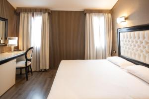 a hotel room with a large bed and a desk at Duomo Boutique Hotel in Chioggia