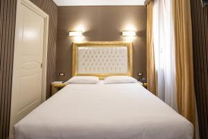a bedroom with a white bed with a gold frame at Duomo Boutique Hotel in Chioggia