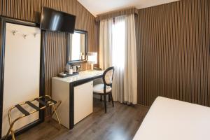 a hotel room with a desk and a bed and a window at Duomo Boutique Hotel in Chioggia